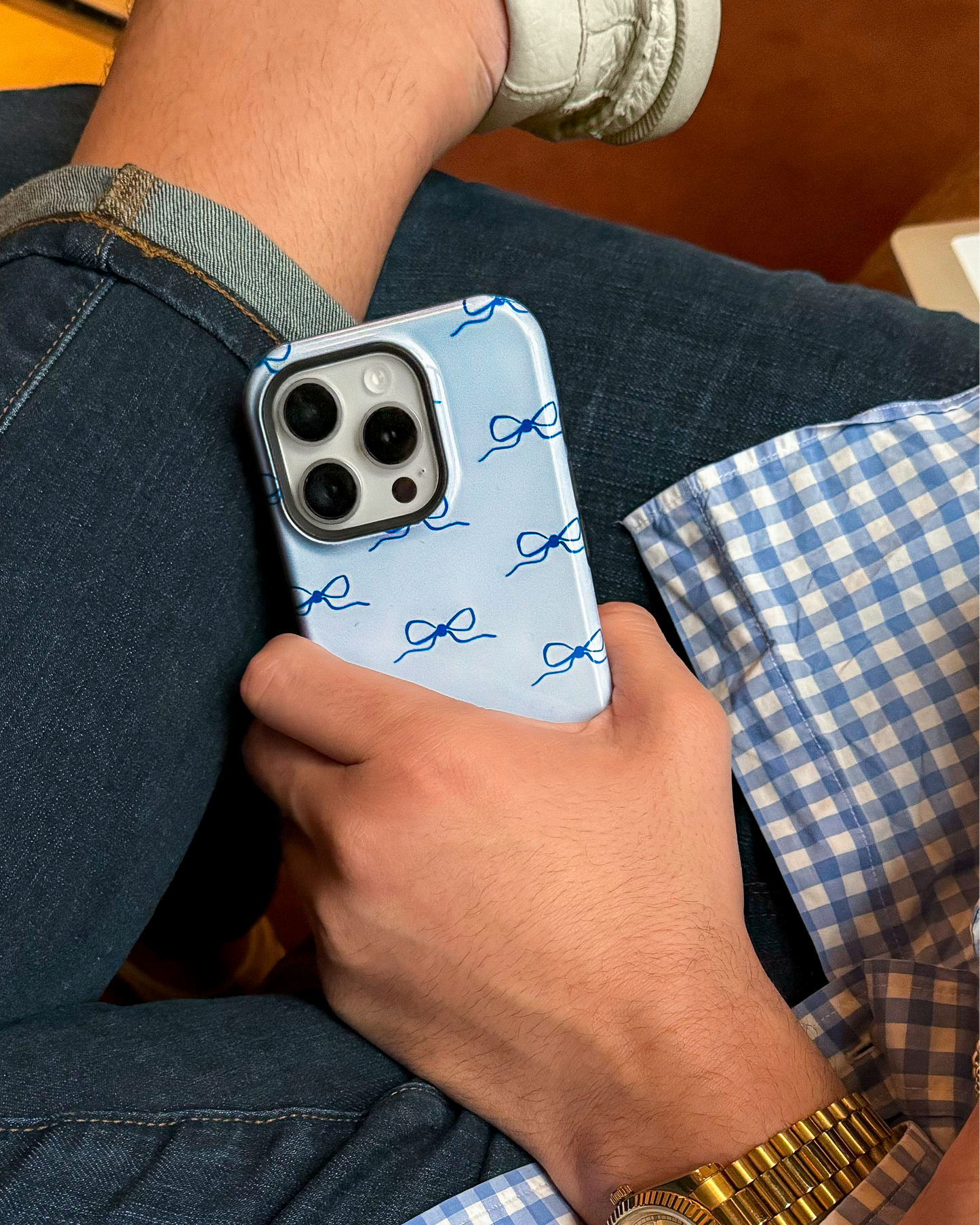 Person holding a phone with a blue case featuring navy blue bows on it.